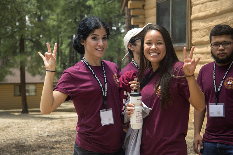 Two young women smile for the camera and display the ASU pitchfork gesture